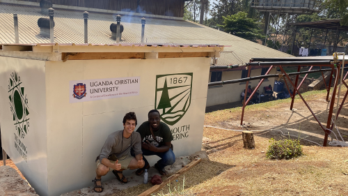 Noah Daniel '22 and Daniel Tumusiime (Uganda Christian University) pose in front of a structure with the Thayer and Irving Institute logo on them