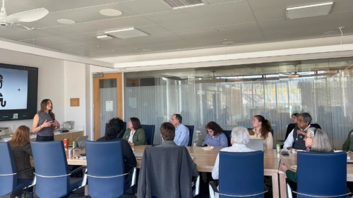 Kimberly Clark, Dartmouth Lecturer, delivers a seminar to a crowd of peers seated at a large table.