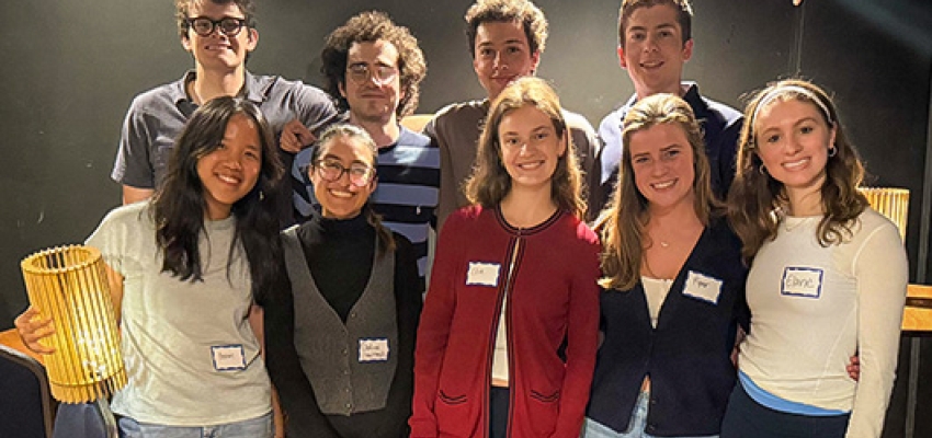 A group of nine students stand together and pose for a photo.