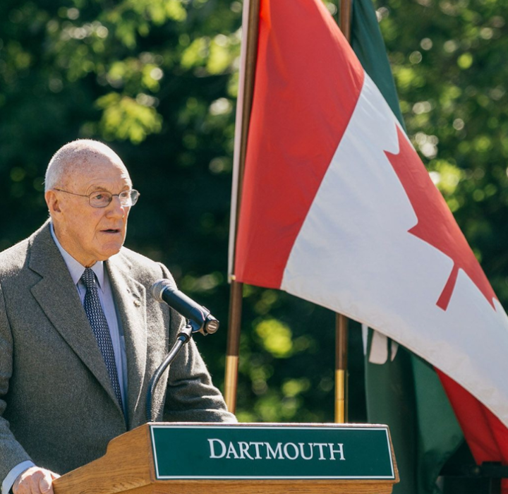 Arthur Irving at a podium that says Dartmouth and a Canadian flag behind him