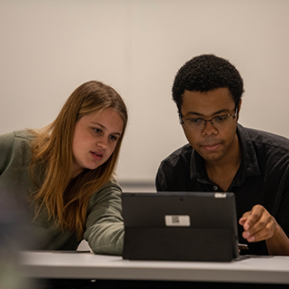 two students collaborating in front of a laptop computer