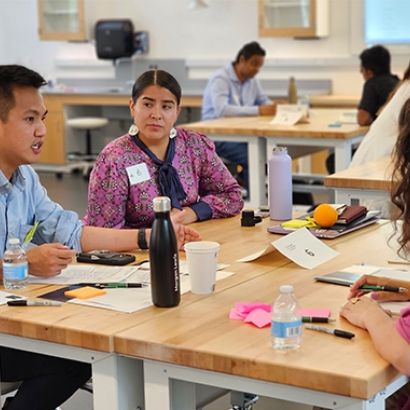 A group of three people sit at a table and talk.