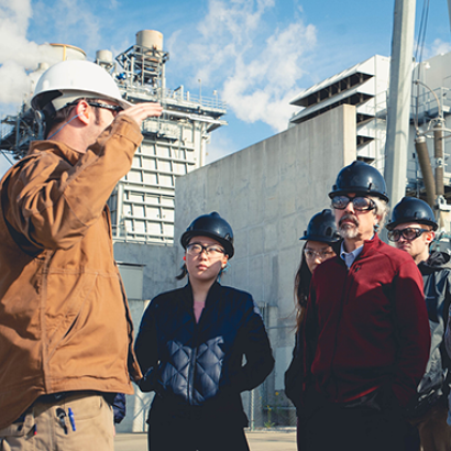 A group standing at an oil refinery listening to a tour guide