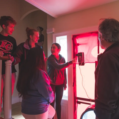 students standing by a door in a room that has a red glow