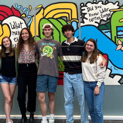 a group of students in front of a colorful mural