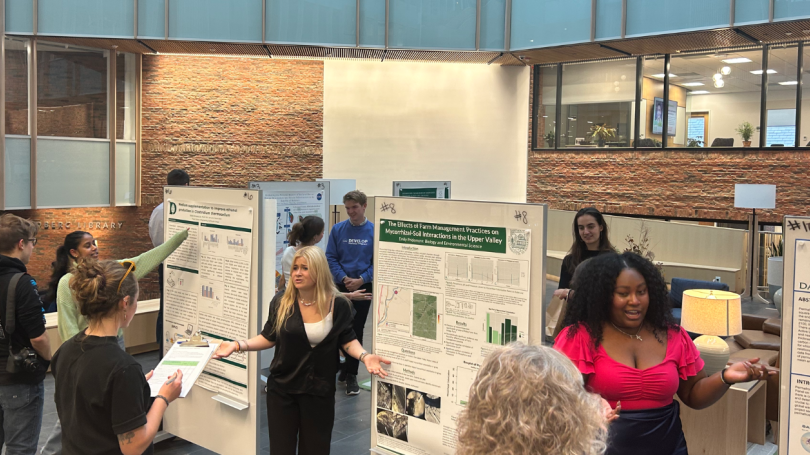 Students in the Irving Institute atrium discussing their posters with audience members