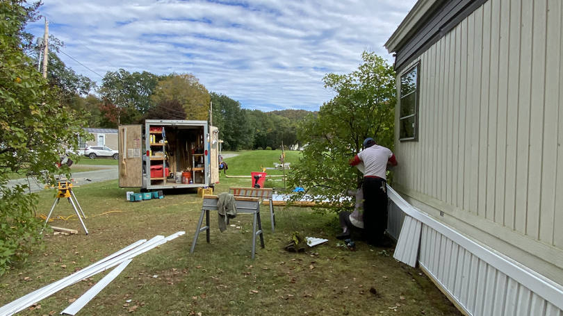 An image of a mobile home and people working on it