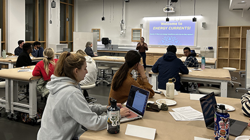 students sitting at tables with a presenter in front of a screen that says Welcome to Energy Currents