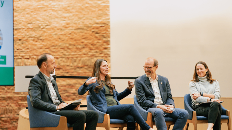 Three people looking at and responding (with interest) to a woman gesturing to emphasize her point