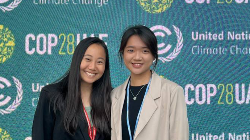 Two women smiling and standing in front of a backdrop that reads United Nations Climate Conference COP28UAE