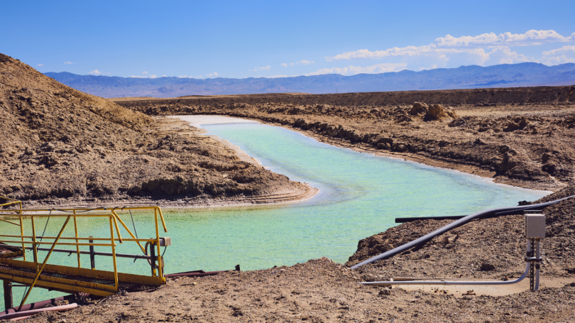 an image of a very blue pool of lithium brine  in a dry and brown landscape