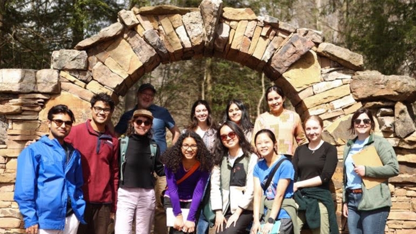 A group of Dartmouth students and Sustainability staff pose beneath a stone archway.