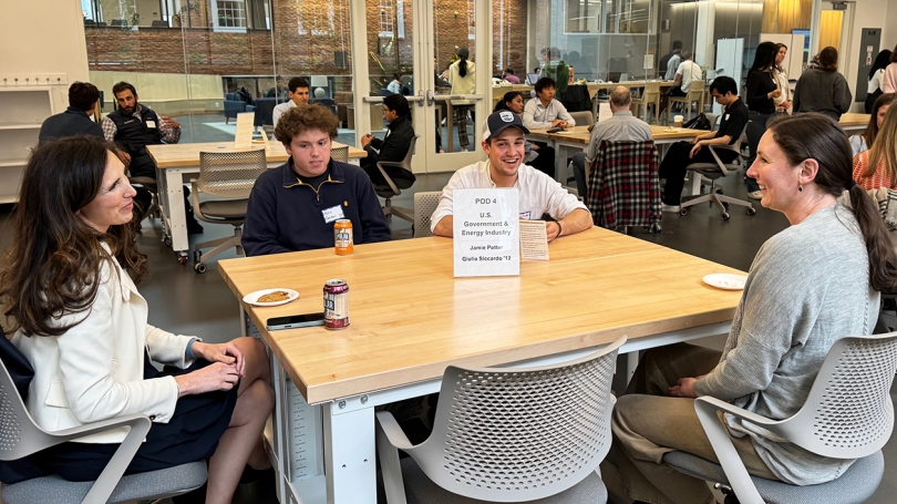 Dartmouth students and professional mentors sit at tables in a large room.