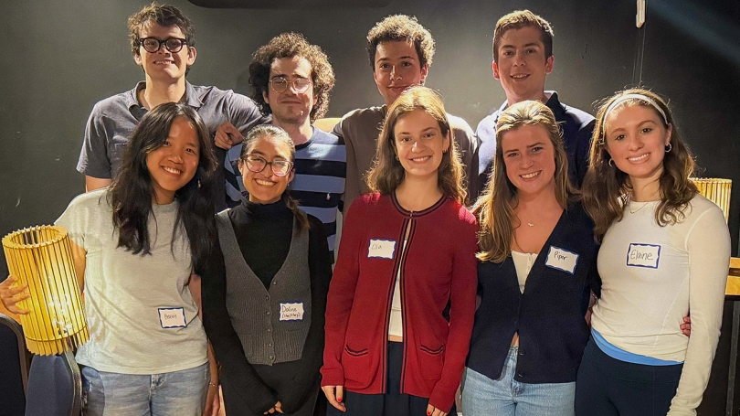 A group of nine students stand together and pose for a photo.