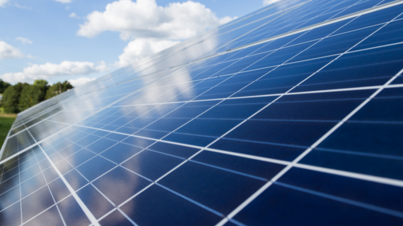 Solar panels with a reflection of clouds and sky