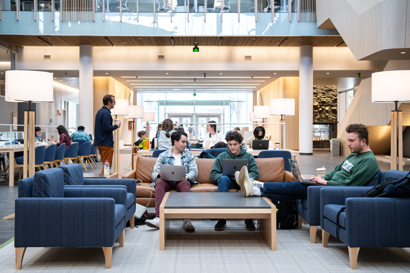 Three students sitting on couches around a coffee table in the Atrium