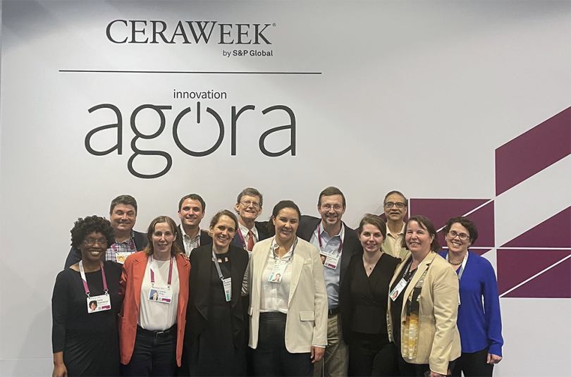 A group of smiling people in front of a sign that says CERAWeek Agora