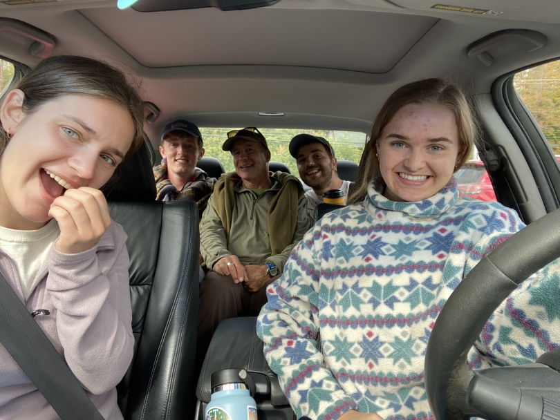 Five people taking a smiling selfie in a car