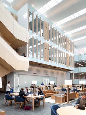 People sit at tables with laptops in the Irving Institute Atrium.