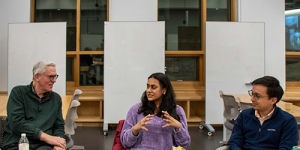 Three people sit at a table and talk with each other.