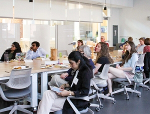 Dartmouth graduate students sit at a long table in a large room.