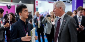 Thayer student Tim Lee meets U.S. Department of Energy Secretary Chris Wright while representing Dartmouth. Dartmouth student Tim Lee talk to U.S. Department of Energy Secretary Chris Wright, in a large room with other people talking to one another.